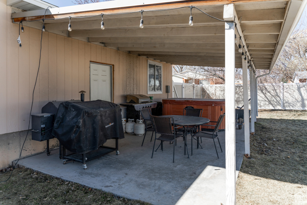View of patio featuring outdoor dining area, area for grilling, a hot tub, and fence