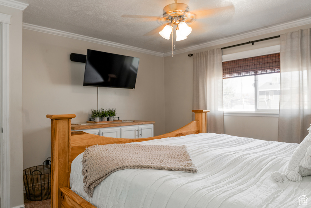 Bedroom featuring a textured ceiling, ornamental molding, and ceiling fan