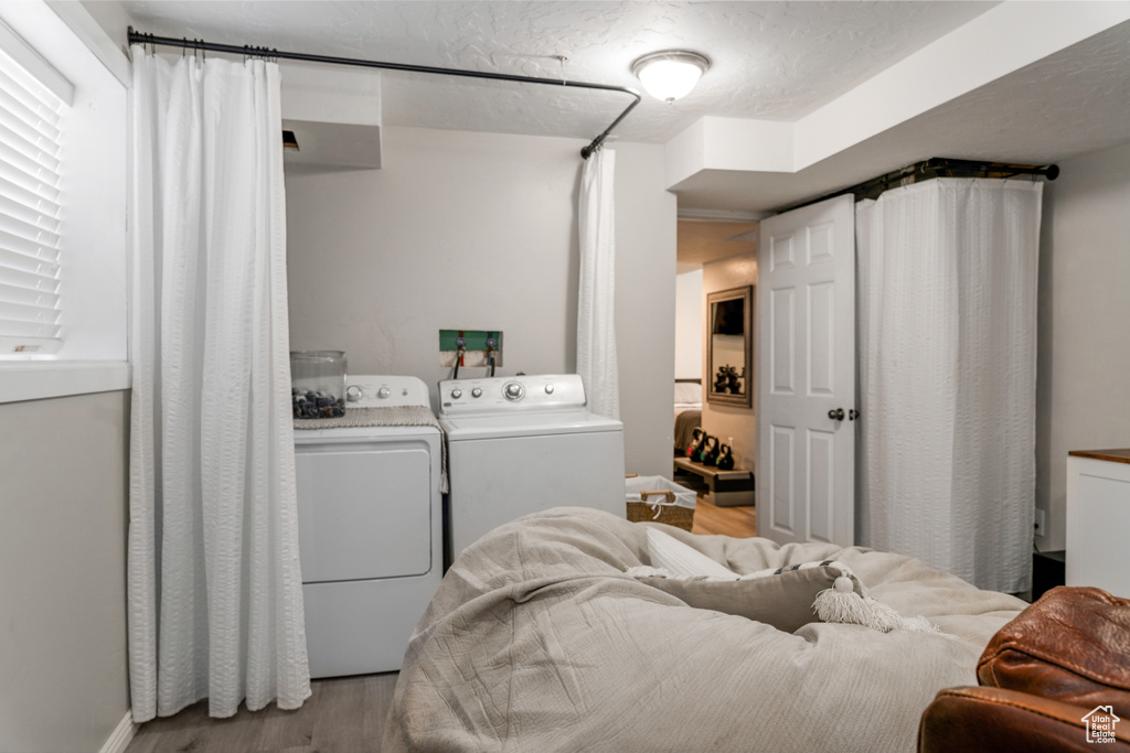 Washroom featuring washing machine and clothes dryer, a textured ceiling, wood finished floors, and laundry area