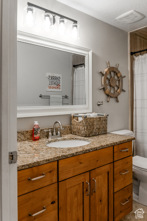 Bathroom with toilet, vanity, and visible vents