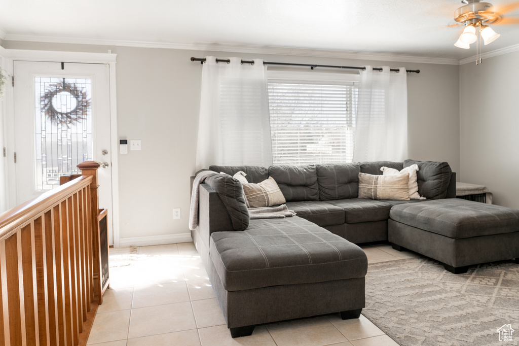 Living room with light tile patterned floors, a ceiling fan, crown molding, and plenty of natural light