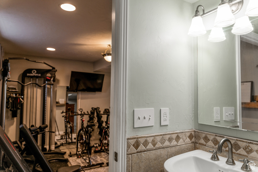 Bathroom featuring a wainscoted wall, a sink, tile walls, and recessed lighting