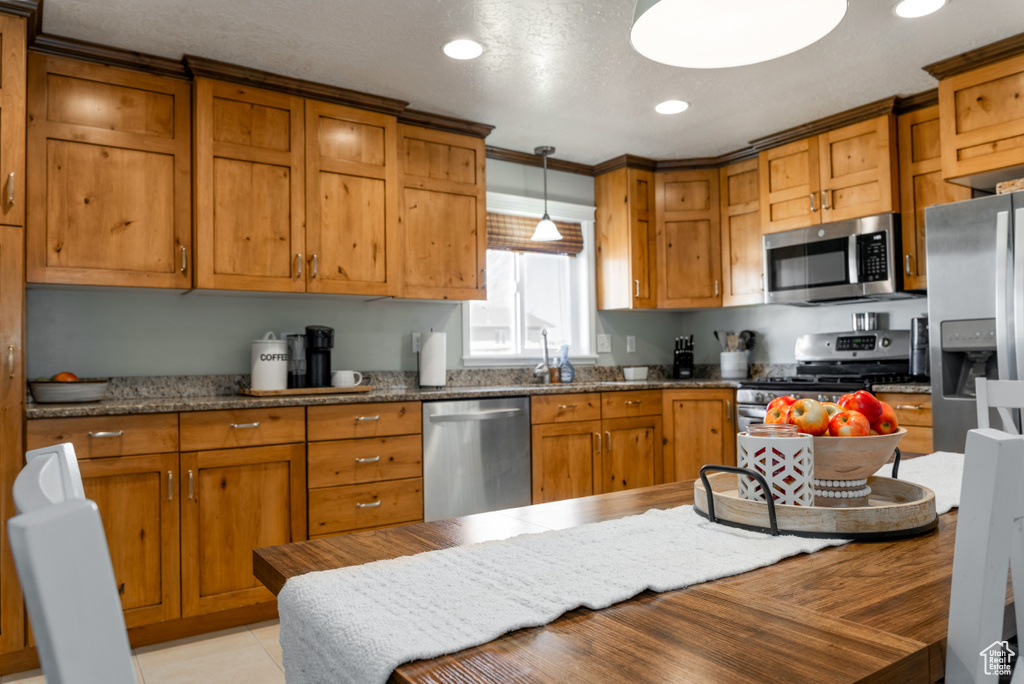 Kitchen featuring hanging light fixtures, brown cabinets, and appliances with stainless steel finishes