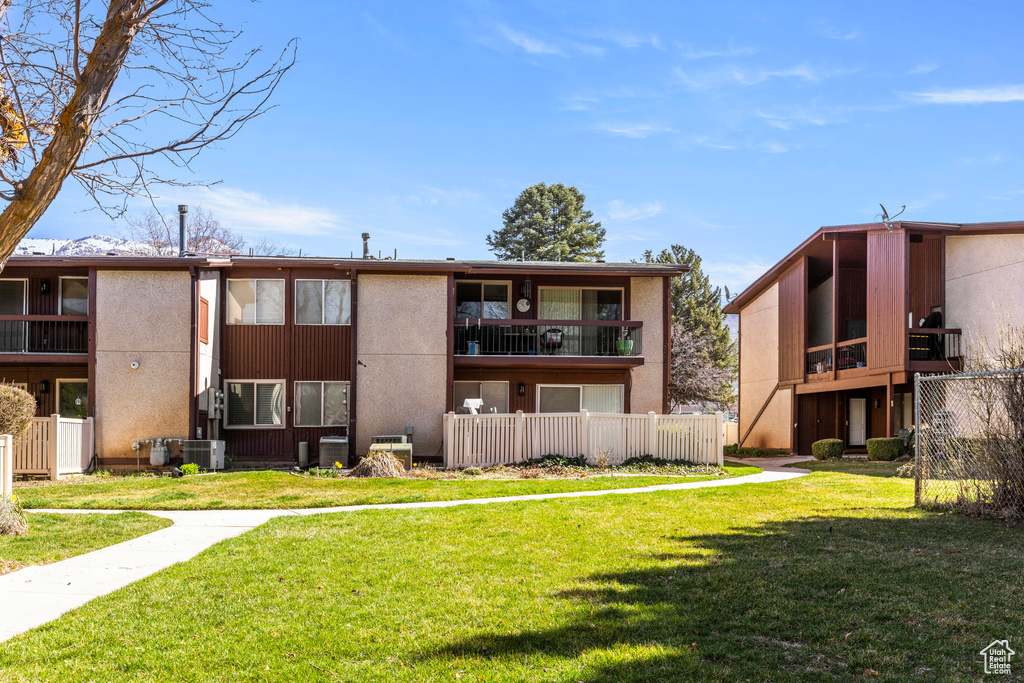 Back of property with a lawn, fence, and stucco siding