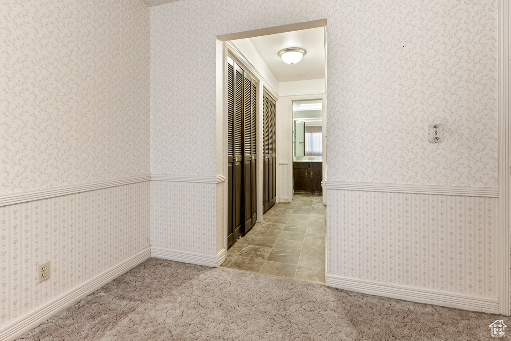 Corridor featuring carpet flooring, wallpapered walls, and a wainscoted wall