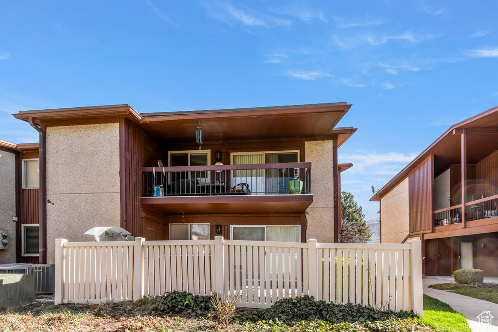 View of front of home featuring a balcony, fence, and stucco siding