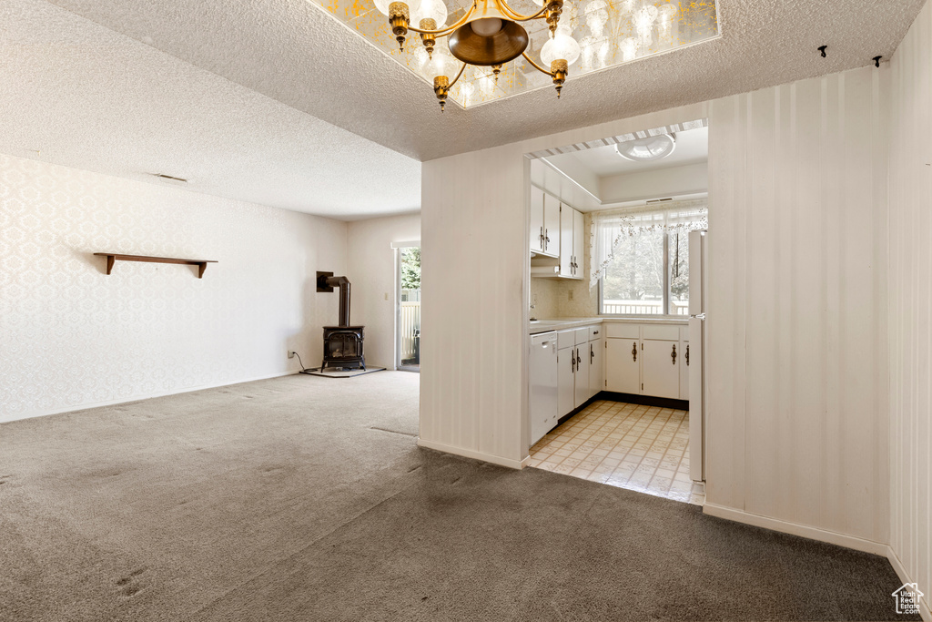 Interior space with light carpet, wallpapered walls, a notable chandelier, and a textured ceiling