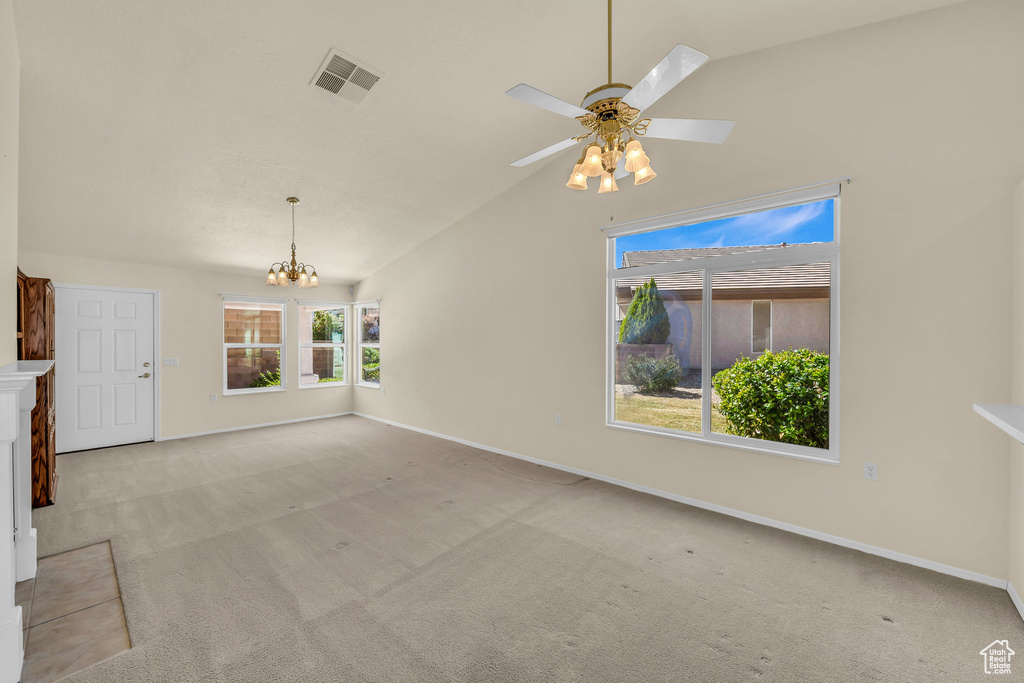Unfurnished living room featuring lofted ceiling, carpet flooring, a chandelier, and a ceiling fan