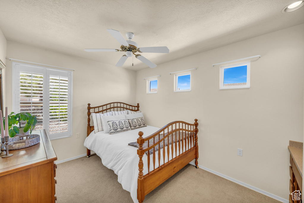 Bedroom with light colored carpet and a ceiling fan