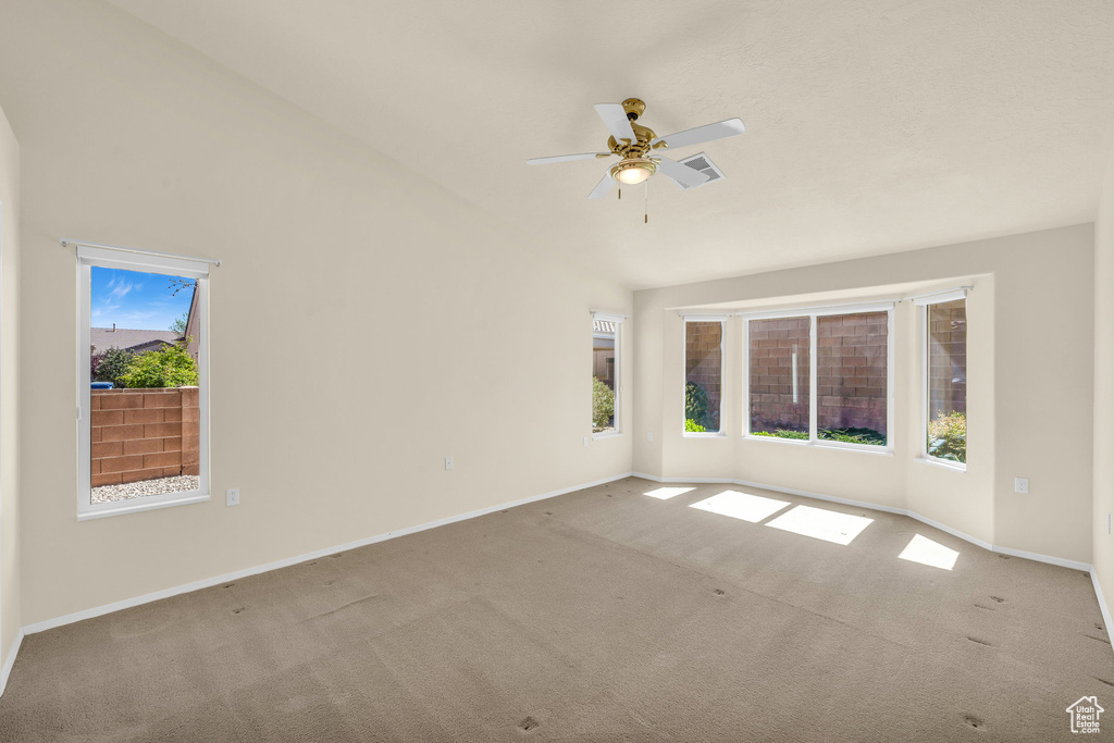 Carpeted spare room featuring plenty of natural light and a ceiling fan