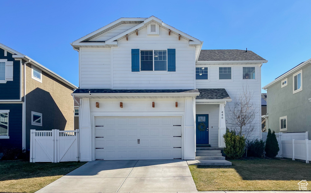 Traditional home featuring fence, concrete driveway, a front yard, and a garage