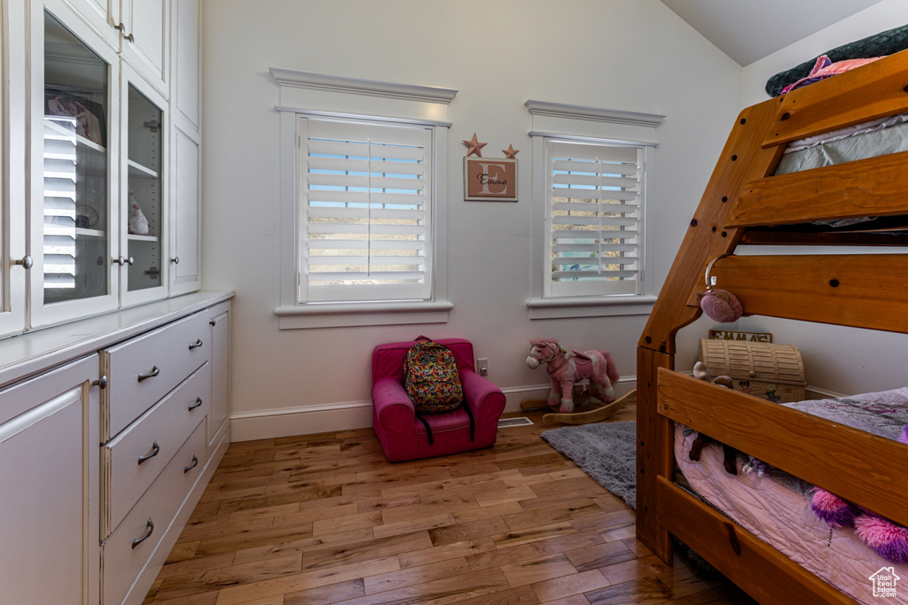 Bedroom featuring light wood-style flooring, multiple windows, and vaulted ceiling
