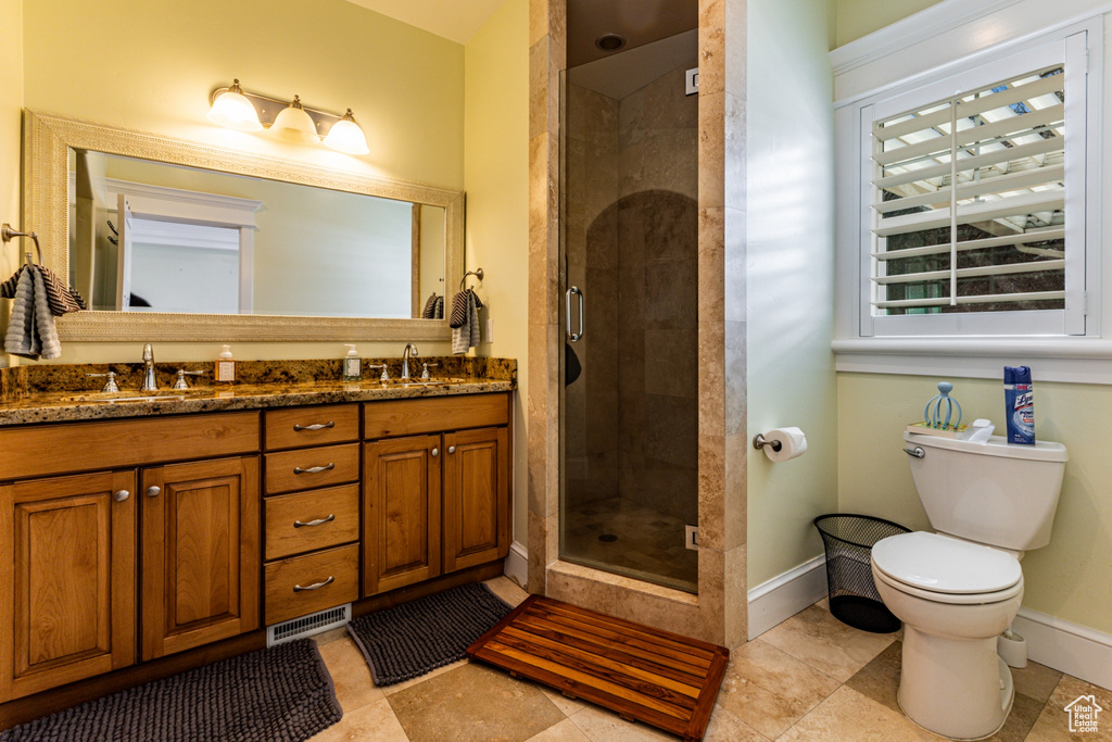 Bathroom with double vanity, a shower stall, and tile patterned flooring