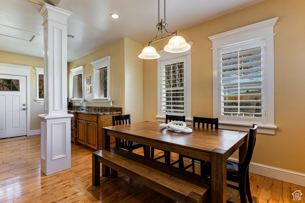 Dining space featuring ornate columns, light wood-style flooring, and recessed lighting