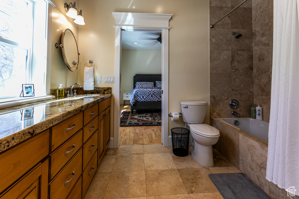 Full bath with ensuite bathroom, tiled shower / bath combo, vanity, and a ceiling fan