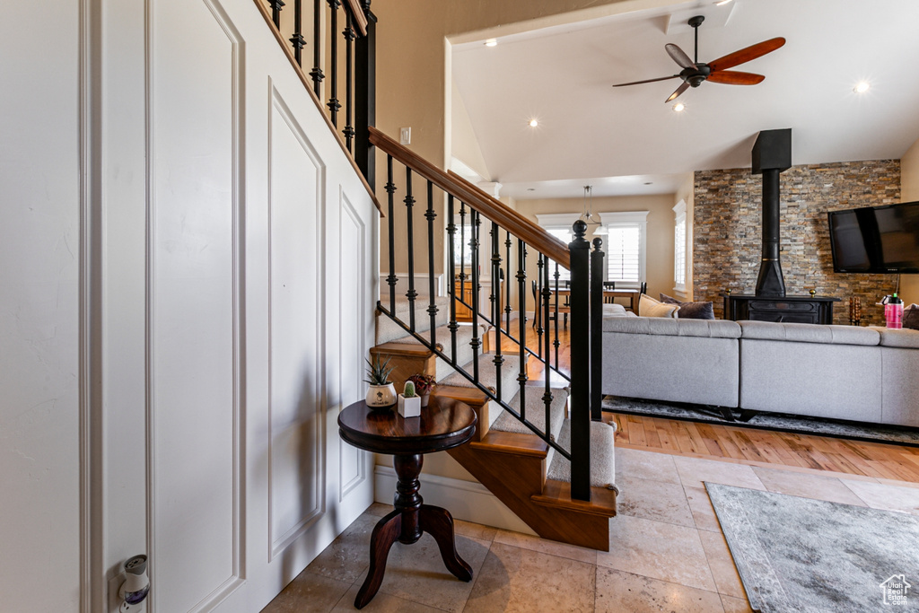 Stairs with a wood stove, vaulted ceiling, a ceiling fan, and recessed lighting