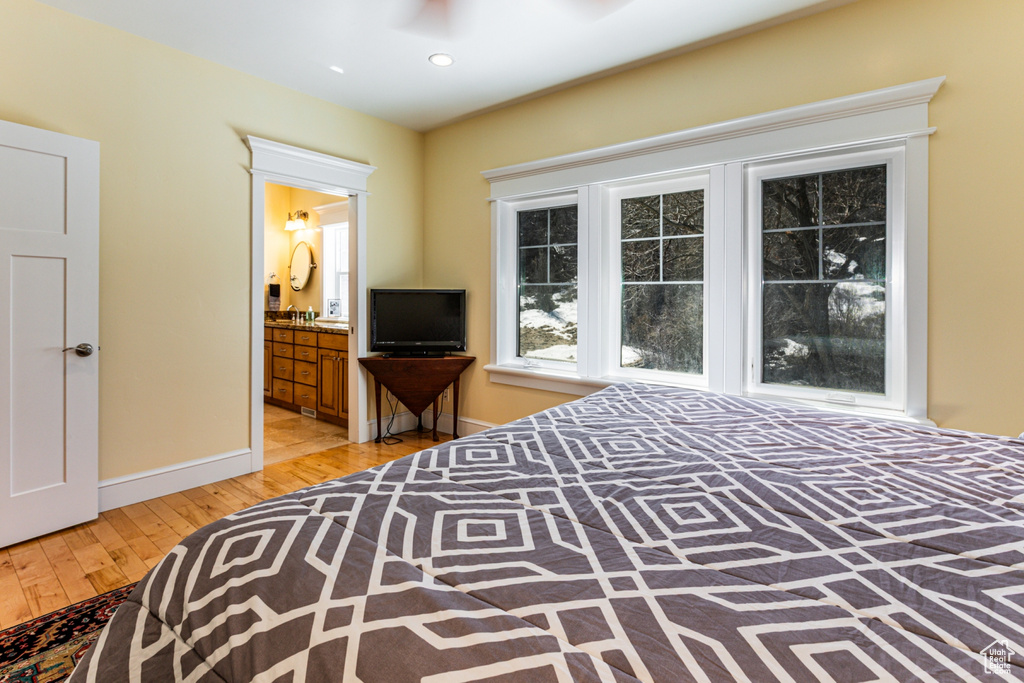 Bedroom with light wood-style flooring, connected bathroom, and recessed lighting