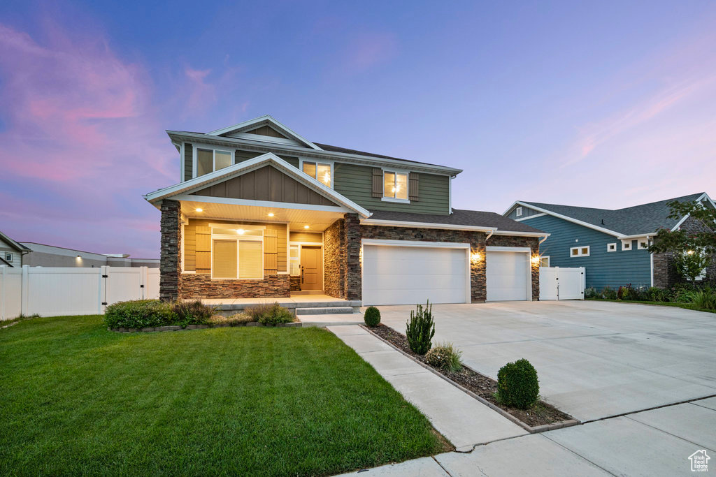 View of front facade featuring stone siding, driveway, a gate, and board and batten siding