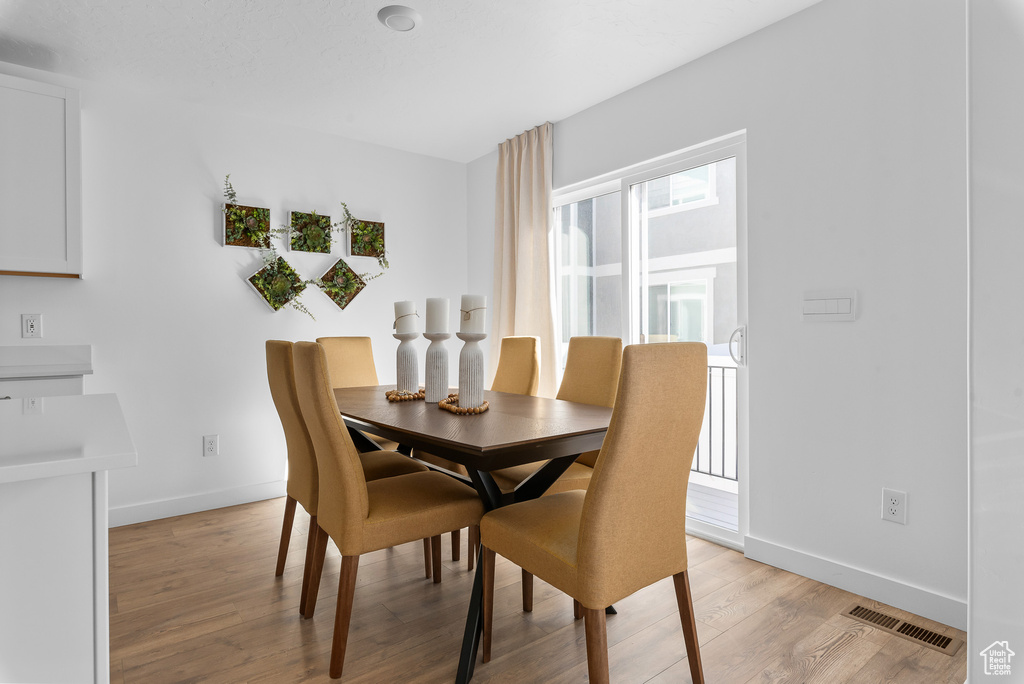 Dining space with baseboards, visible vents, and light wood-type flooring