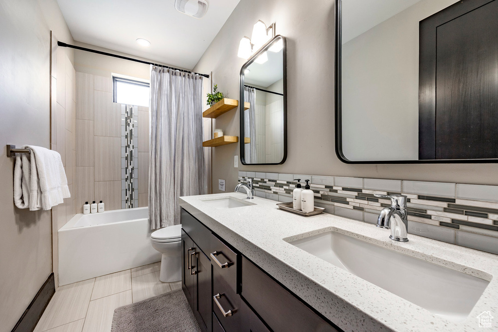 Bathroom with toilet, tasteful backsplash, a sink, and shower / bath combo
