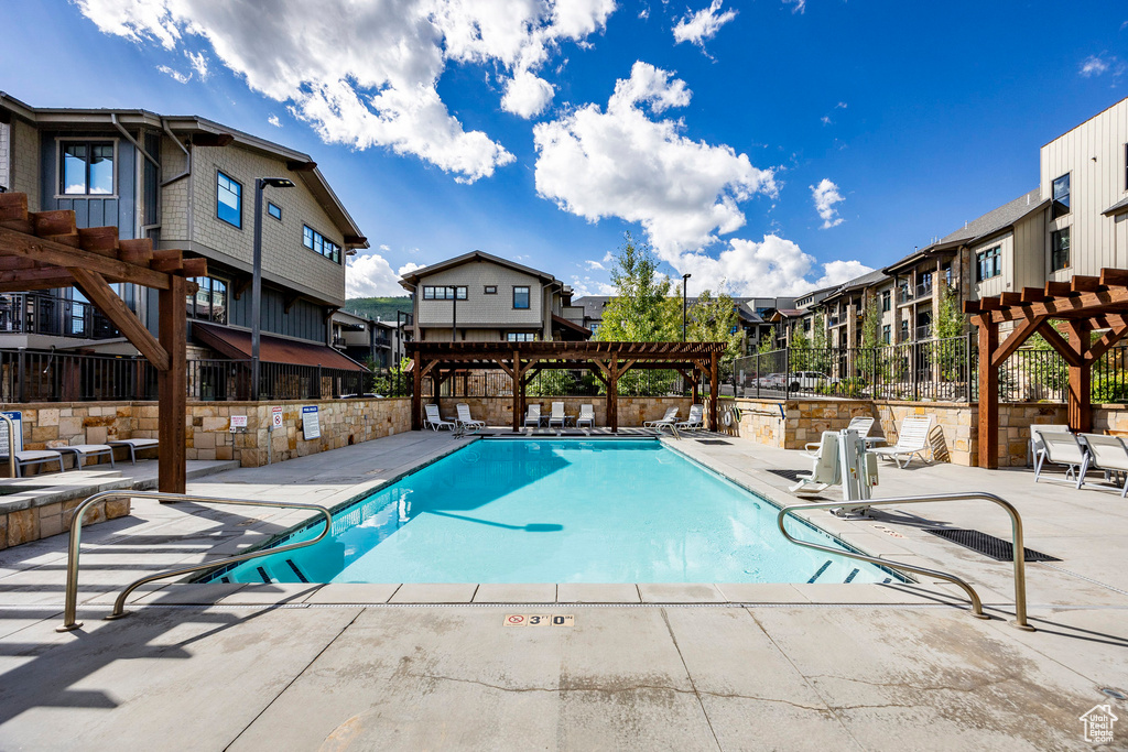 Pool with a pergola, a patio area, a residential view, and fence