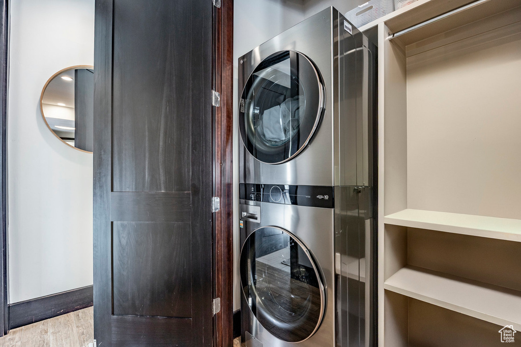 Laundry room with stacked washer / drying machine, laundry area, and wood finished floors