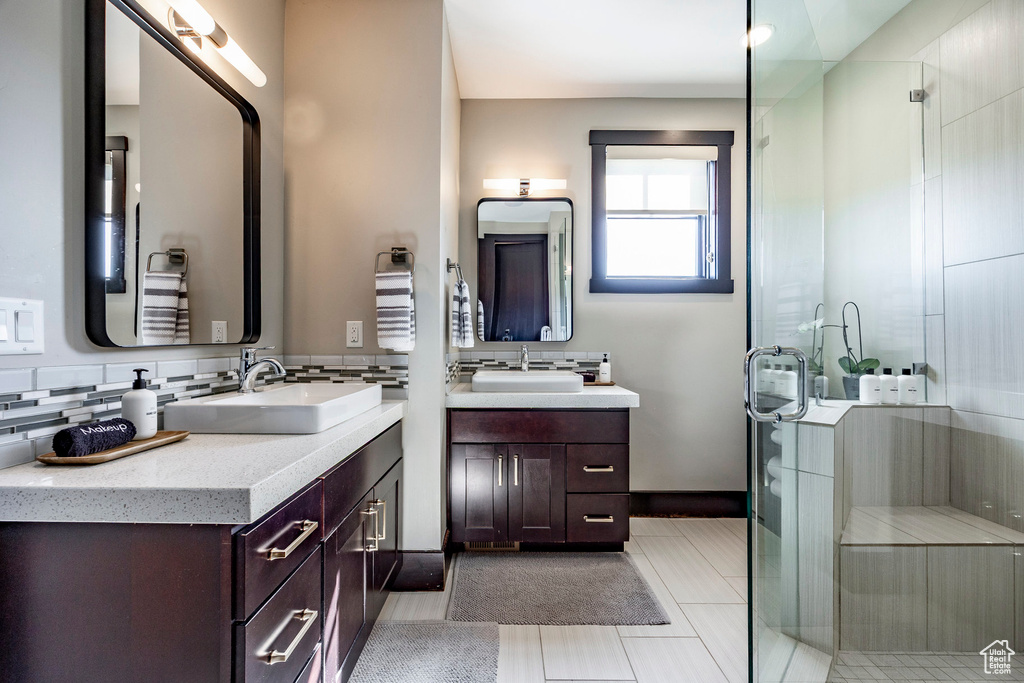 Bathroom with a stall shower, two vanities, decorative backsplash, and a sink