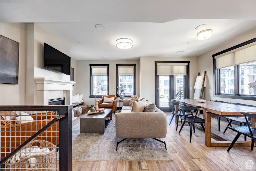 Living room featuring a glass covered fireplace, plenty of natural light, visible vents, and wood finished floors