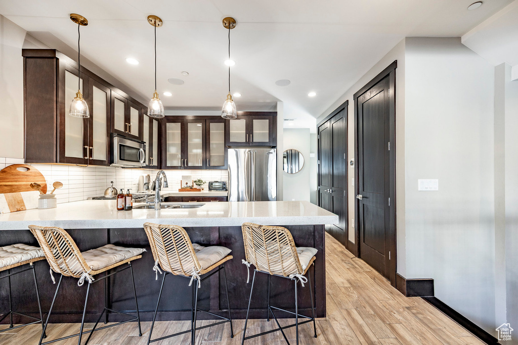 Kitchen featuring light countertops, a peninsula, a sink, and stainless steel appliances