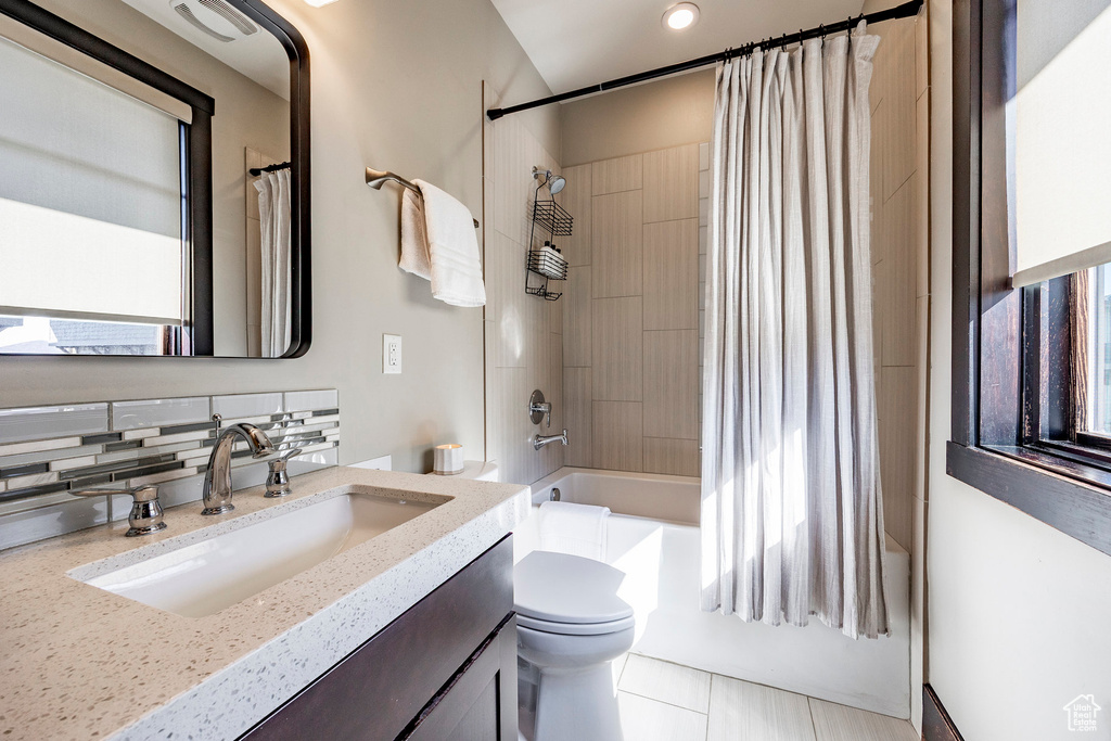 Full bath featuring shower / bath combo, backsplash, toilet, and vanity