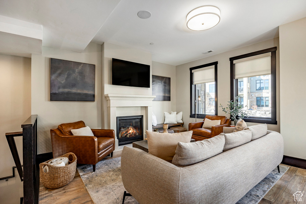 Living area featuring visible vents, wood finished floors, and a glass covered fireplace
