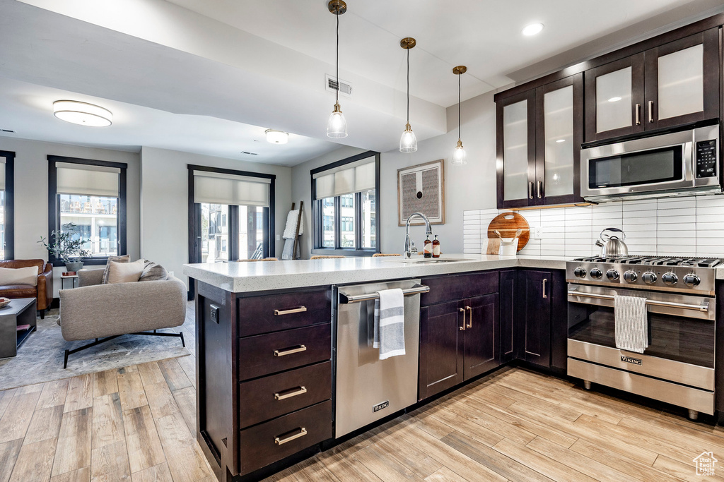 Kitchen with a peninsula, visible vents, appliances with stainless steel finishes, light countertops, and a sink
