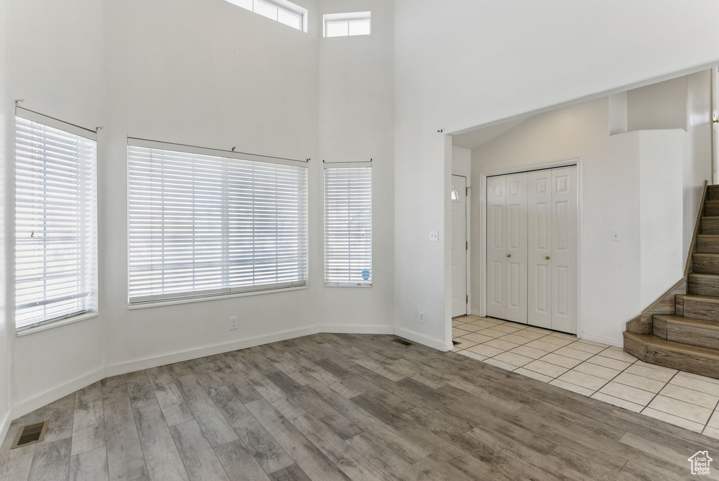 Foyer featuring stairway, a high ceiling, wood finished floors, baseboards, and visible vents
