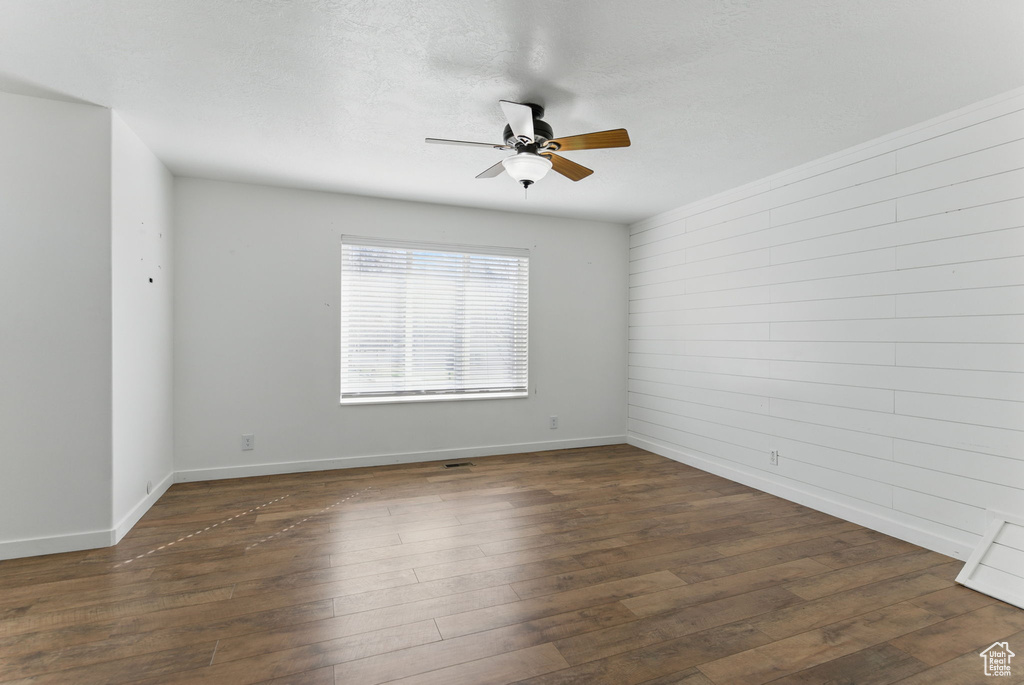 Unfurnished room with baseboards, a textured ceiling, dark wood-style floors, and a ceiling fan