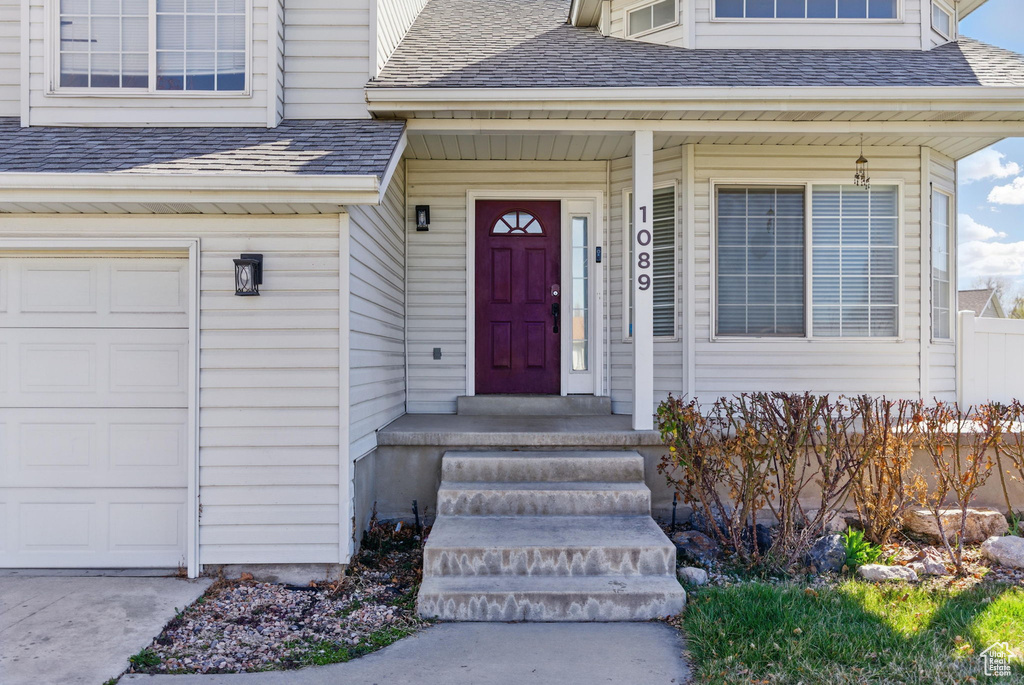 Entrance to property with a garage and roof with shingles