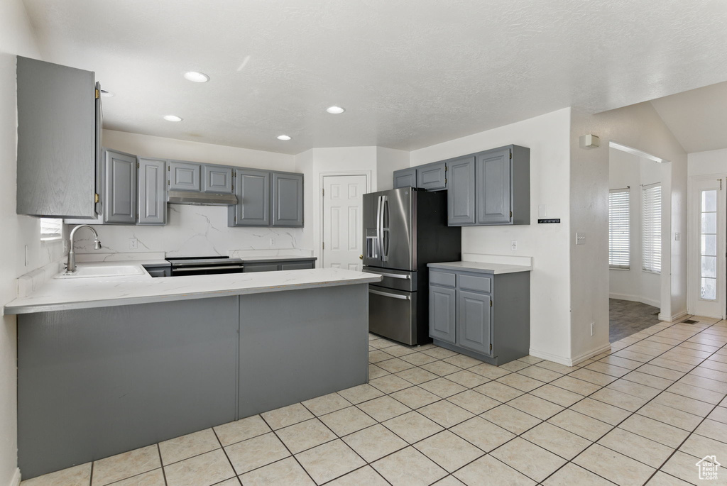 Kitchen with light countertops, gray cabinetry, a sink, a peninsula, and appliances with stainless steel finishes