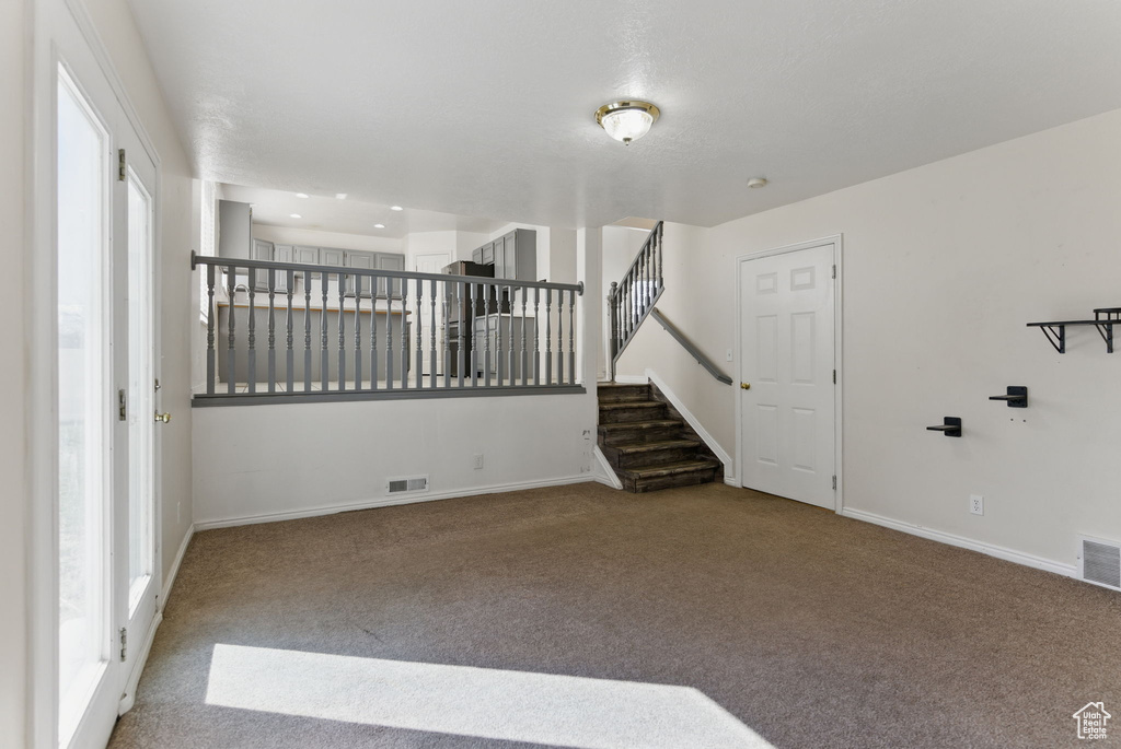 Carpeted spare room with baseboards, visible vents, stairs, and recessed lighting