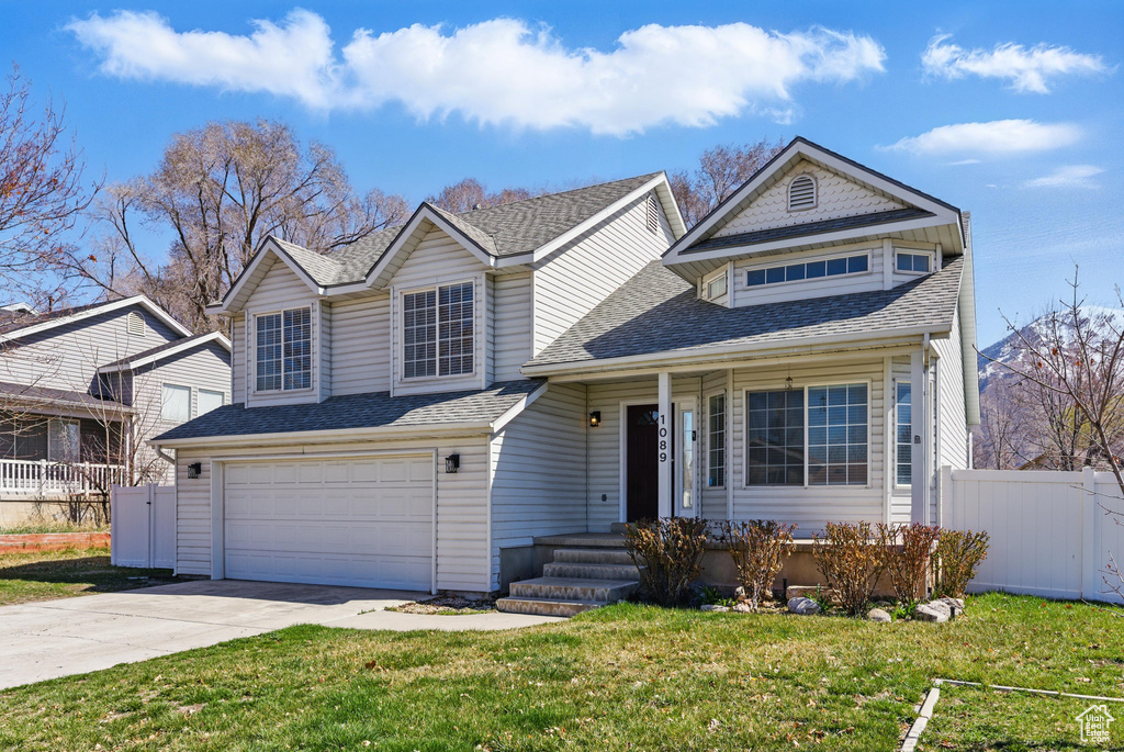 View of front facade with a shingled roof, an attached garage, fence, and concrete driveway
