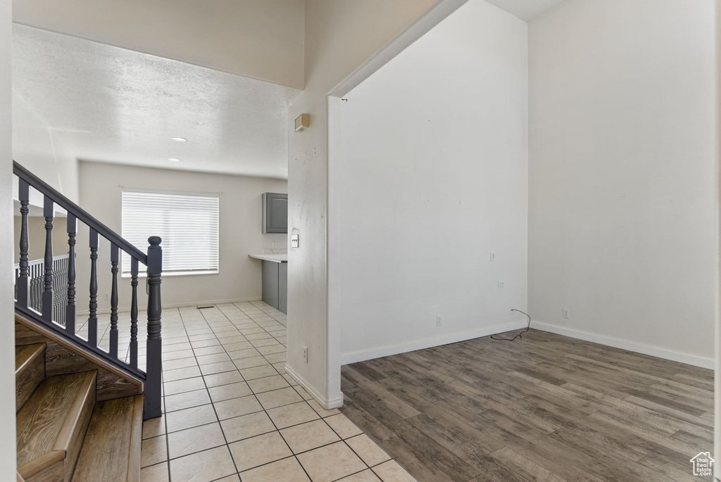Entryway featuring light tile patterned floors, baseboards, stairs, and a textured ceiling