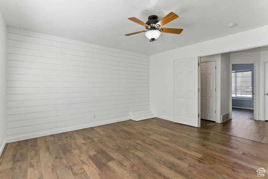 Unfurnished bedroom with dark wood-style flooring, baseboards, and ceiling fan