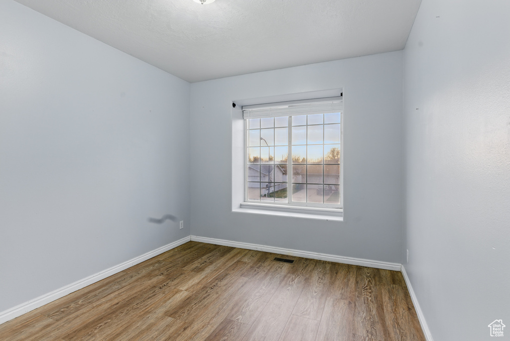 Spare room with baseboards, visible vents, and wood finished floors