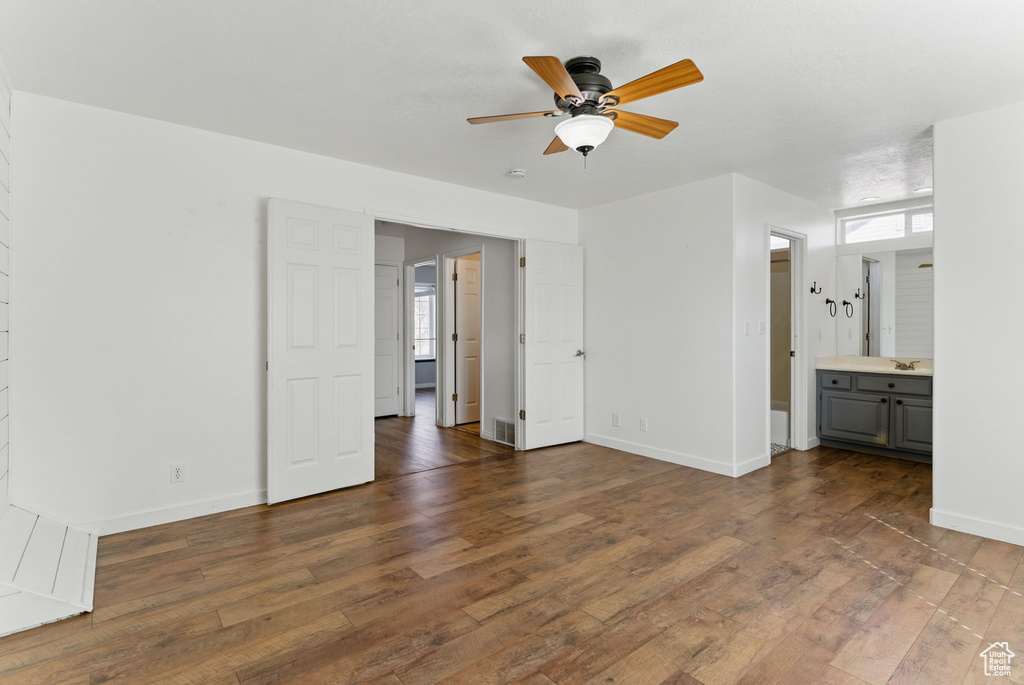 Interior space featuring a sink, ensuite bathroom, hardwood / wood-style flooring, and baseboards