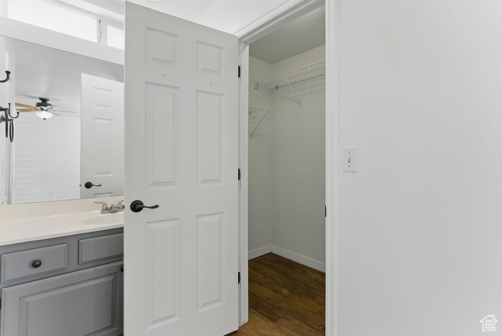 Bathroom with baseboards, wood finished floors, vanity, and a ceiling fan