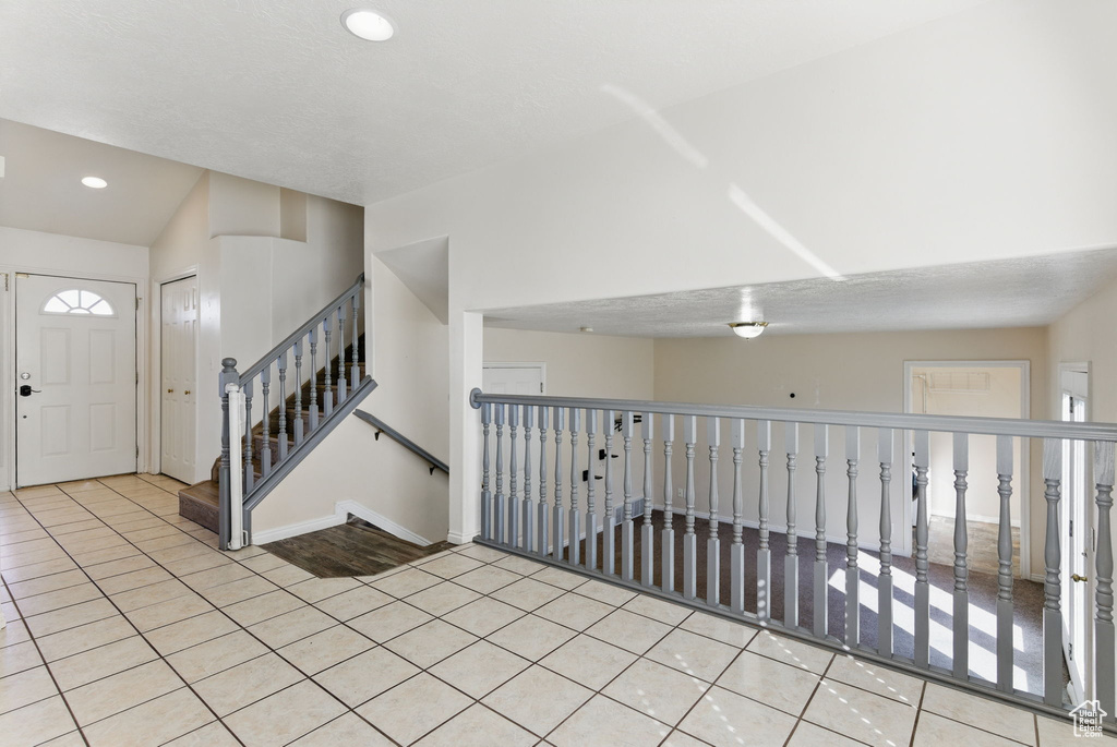 Foyer featuring tile patterned flooring, baseboards, lofted ceiling, and recessed lighting