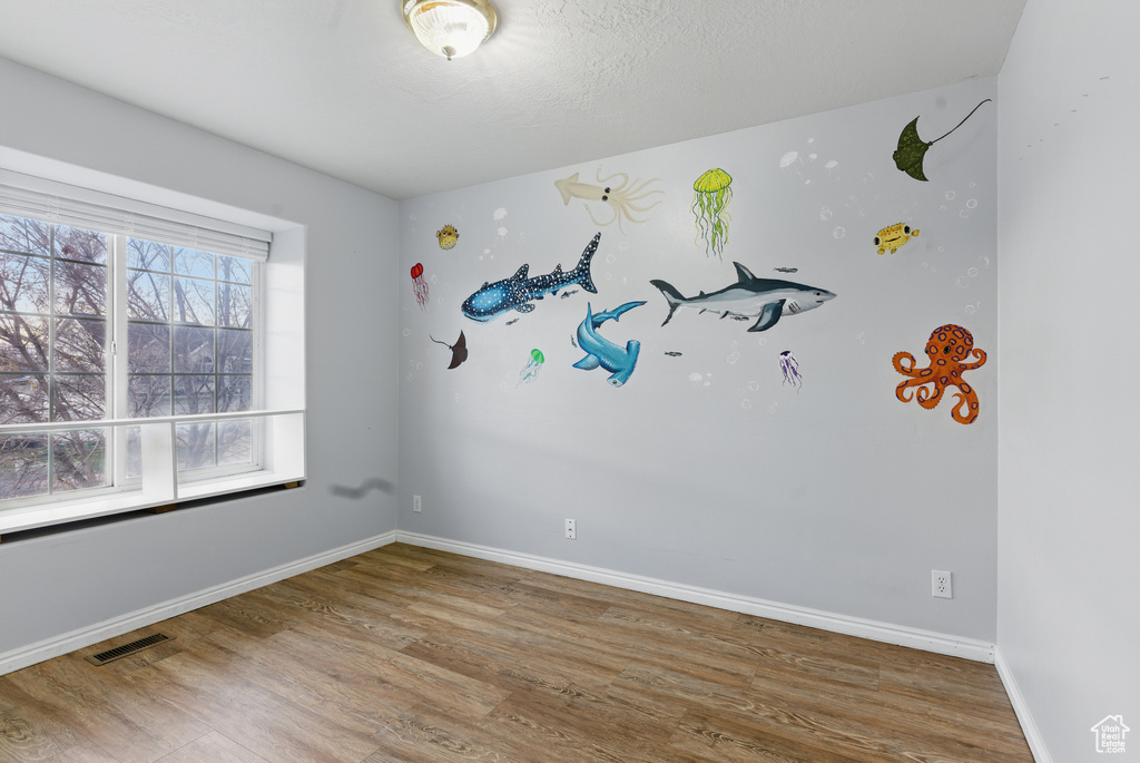 Unfurnished room featuring wood finished floors, baseboards, and visible vents