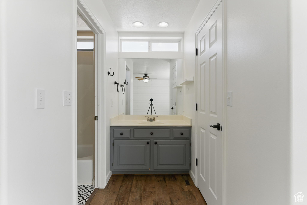 Bathroom featuring a textured ceiling, a ceiling fan, wood finished floors, and vanity