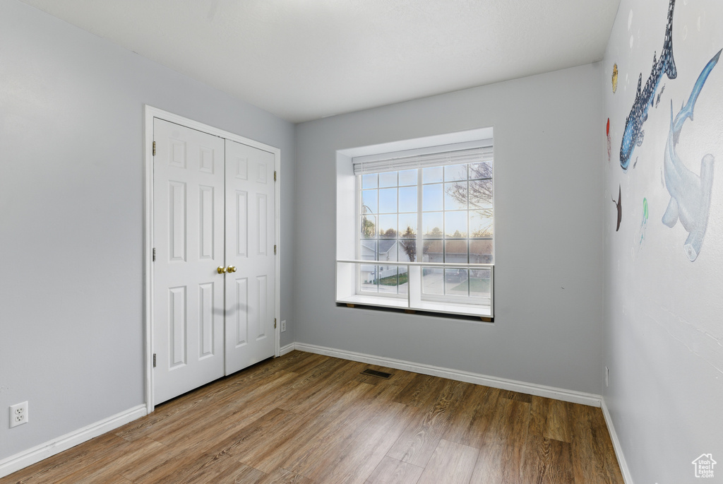 Unfurnished bedroom with baseboards, visible vents, a closet, and wood finished floors