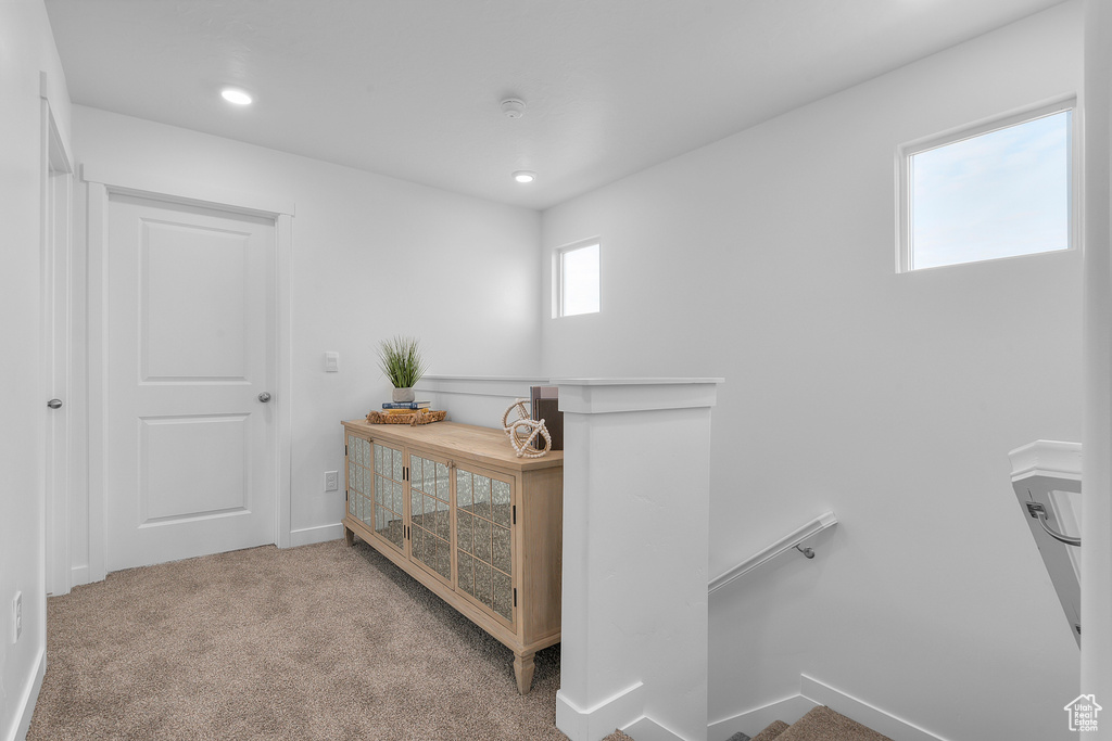 Hallway featuring baseboards, carpet floors, an upstairs landing, and recessed lighting