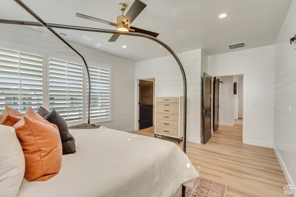 Bedroom featuring light wood-style flooring, visible vents, recessed lighting, and wood walls