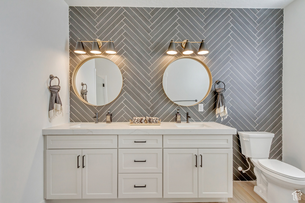 Full bath featuring toilet, a sink, and double vanity